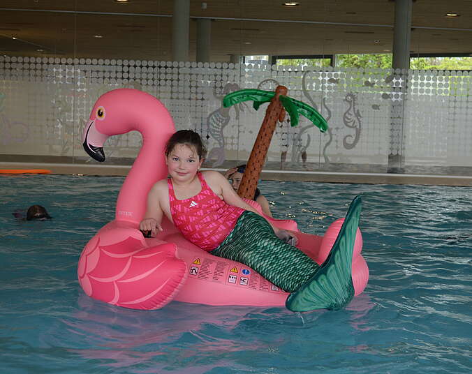 Kind mit Meerjungfrauenflosse auf Schwimmtier