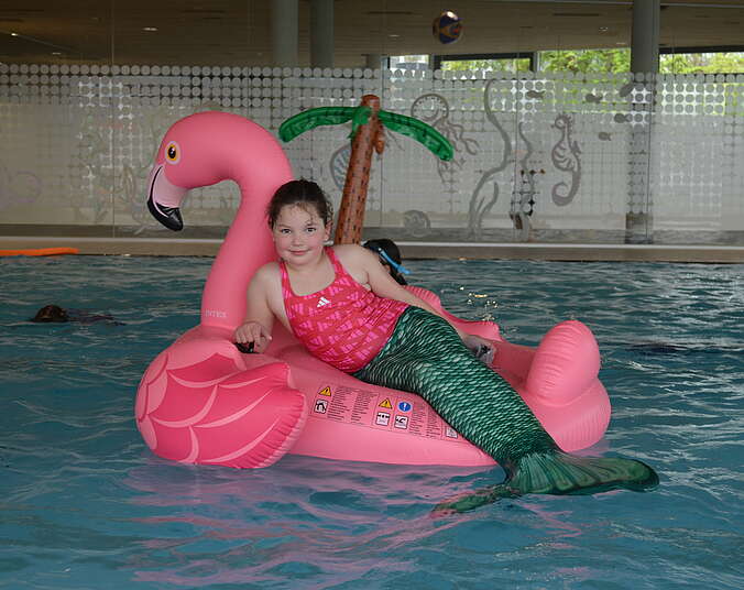 Kind mit Meerjungfrauenflosse auf Schwimmtier