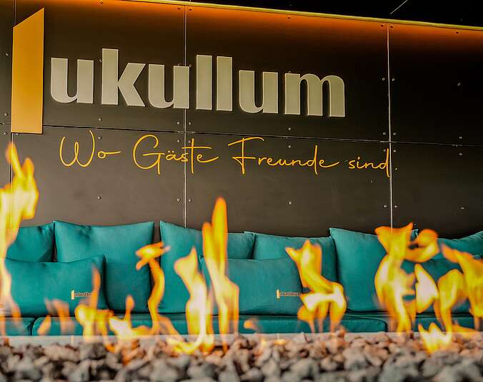 Feuerstelle in der Skybar des Lukullum, bunte Wand im Hintergrund mit Schriftzug lukullum - wo Gäste Freunde sind.