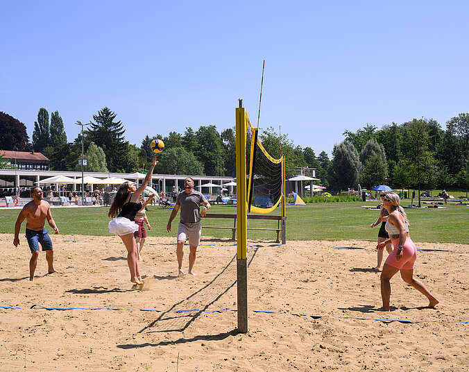 Mehrere Personen spielen Beachvolleyball