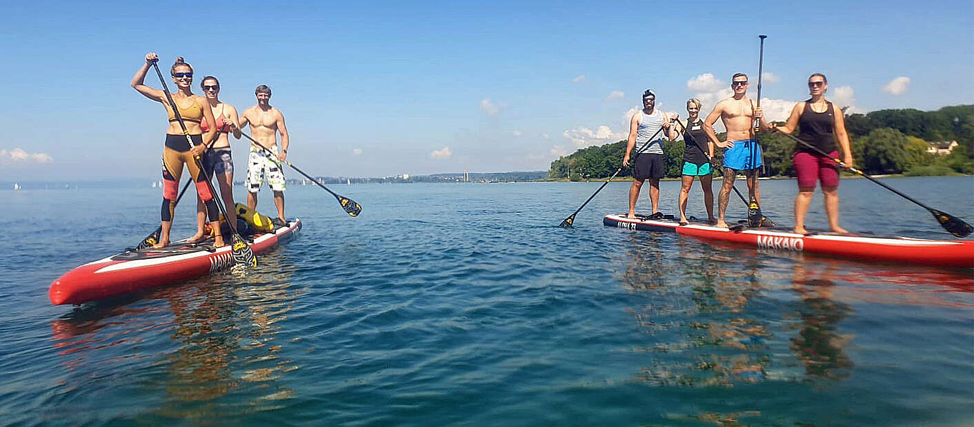 8 Menschen auf 2 Stand up Paddles im See