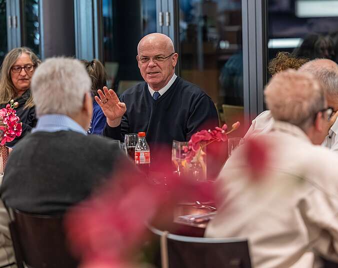 Männer und Frauen sitzen an einem festlich gedeckten Tisch.
