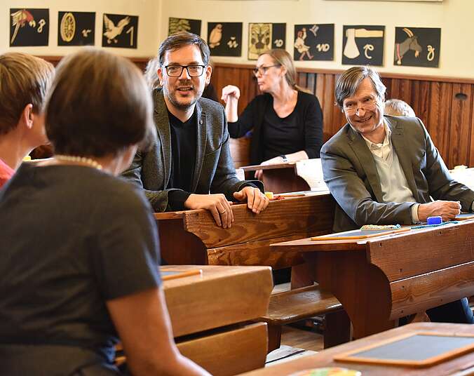 Menschen diskutieren im hstorischen Klassenzimmer miteinander