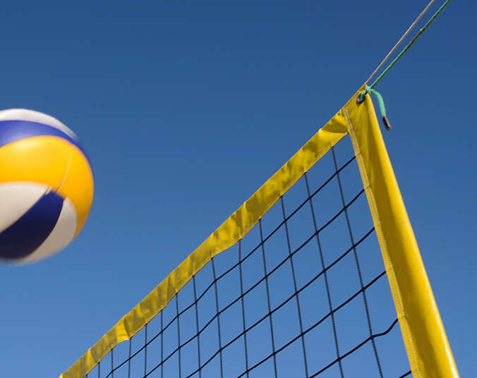 Volleyball fliegt übers Netz. (Foto: Canva)