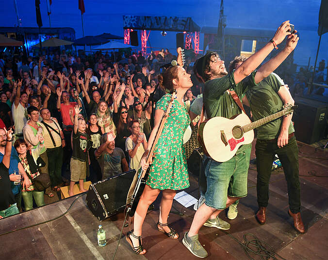Band auf einer Bühne am See